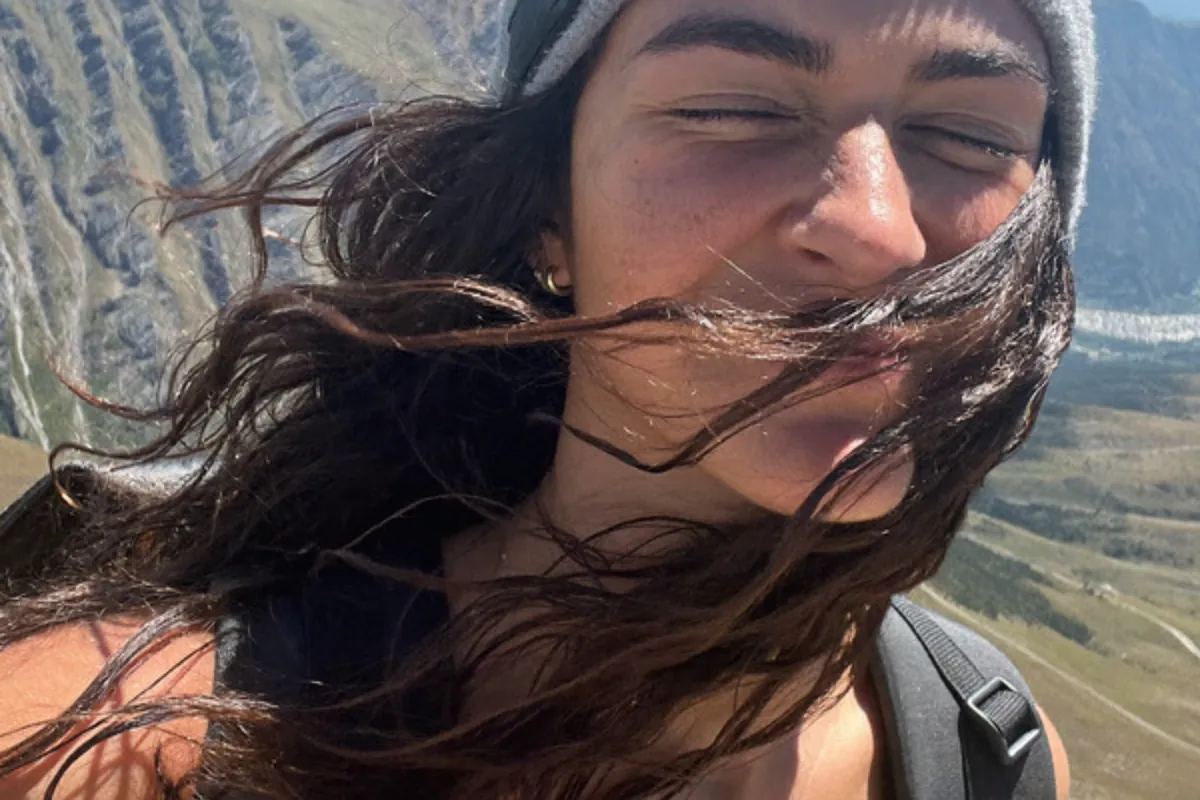 Postcard front with a single windblown selfie on a mountain trail filling the whole card