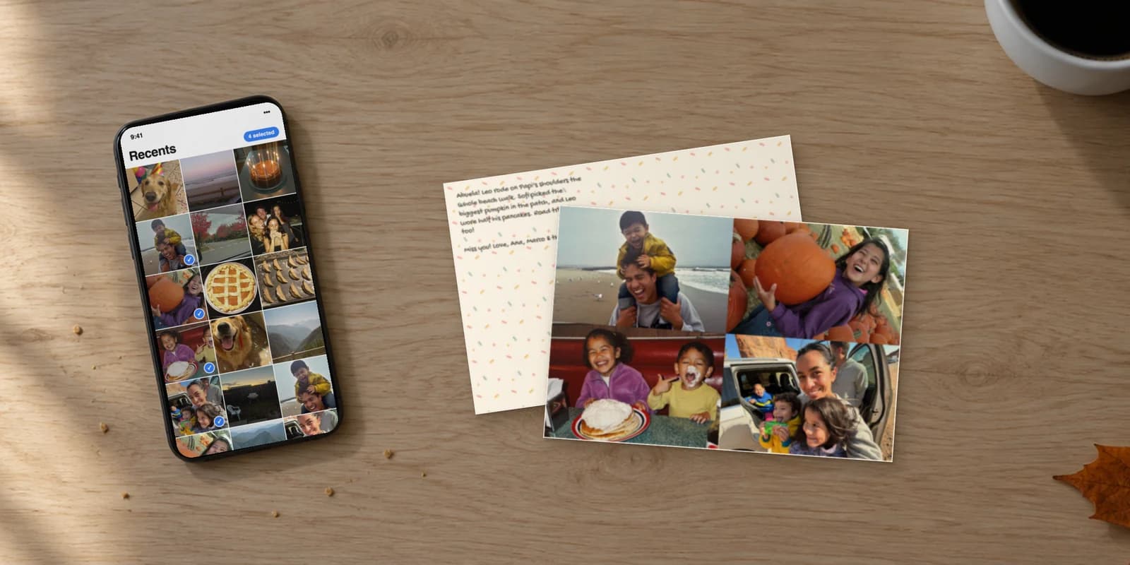 Custom photo postcard printed from four phone photos, lying on a kitchen table next to the phone they were picked from