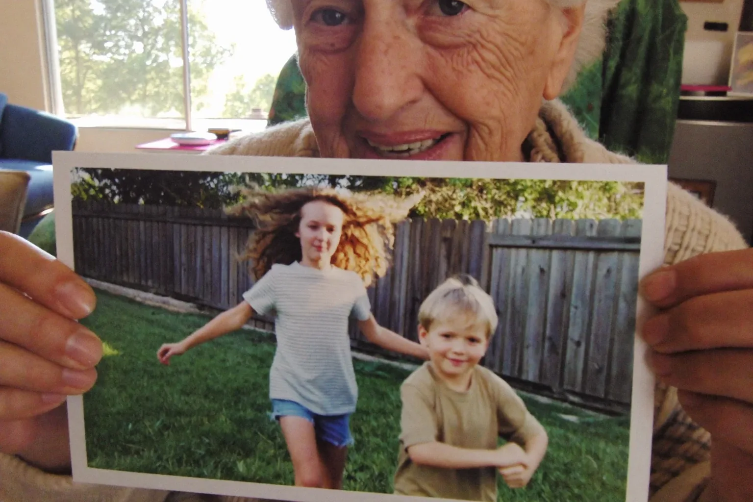 Gifts for grandma: a grandmother holding a printed 4×6 photo of her grandchildren