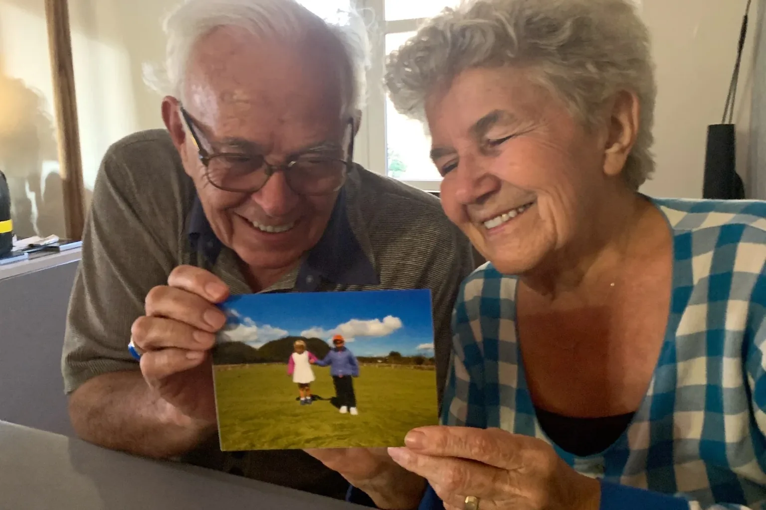 Gifts for grandpa and grandma: a grandfather and grandmother looking together at one printed 4×6 photo card