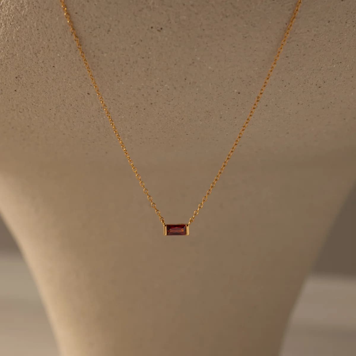A dainty gold birthstone pendant necklace on a fine chain