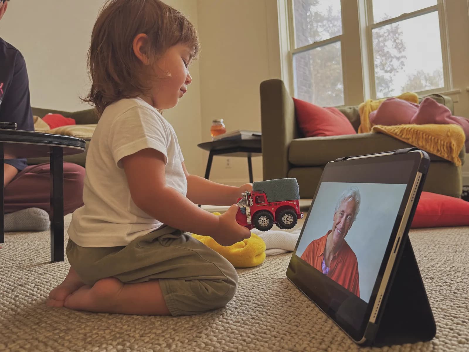 A toddler showing a toy to a grandparent during a short video call