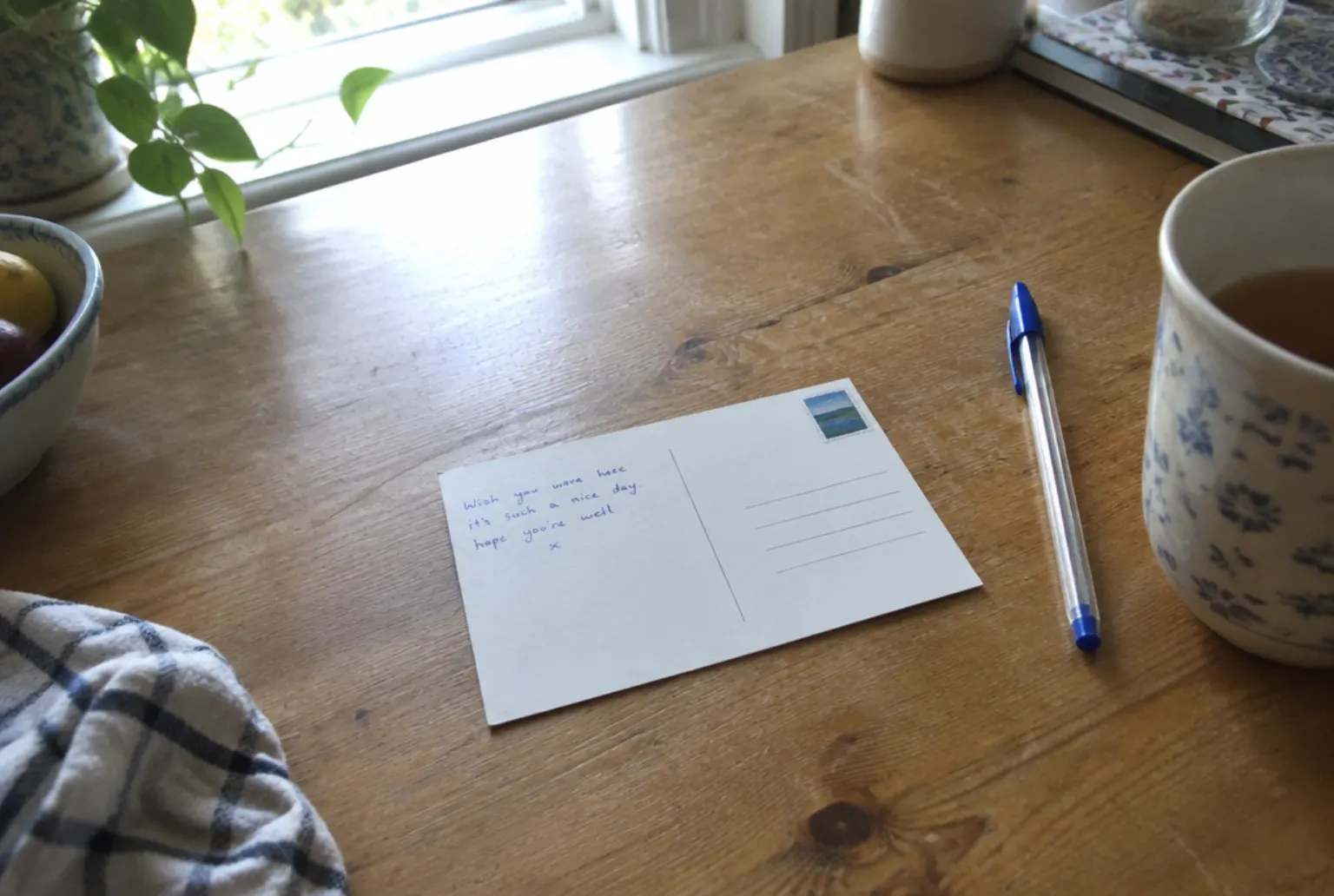 Grandma quotes on a card: a 4x6 postcard face down on a kitchen table with one short line written on the back and a pen beside it
