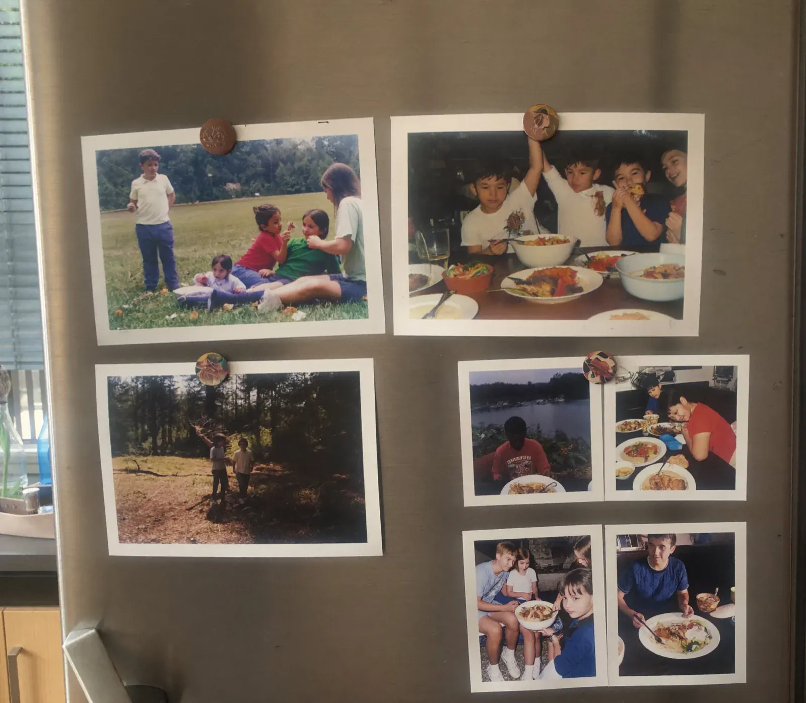 Five FamilyLetter postcards held to a refrigerator door with magnets, some with one photo and some a collage