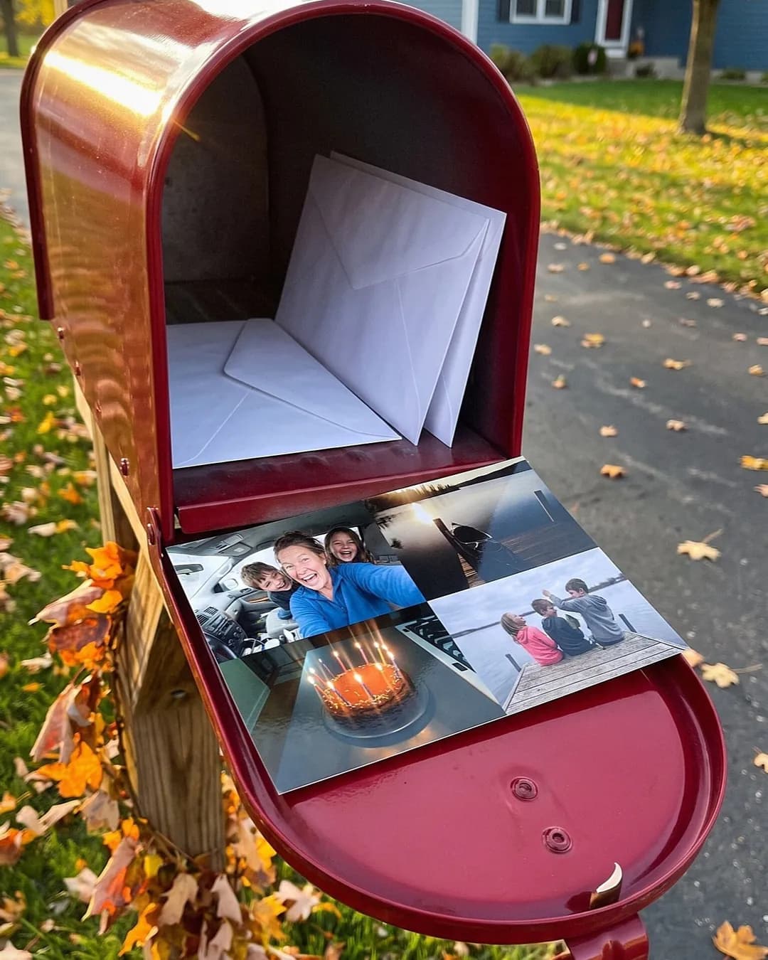 A photo postcard of four family pictures resting on an open red mailbox in autumn