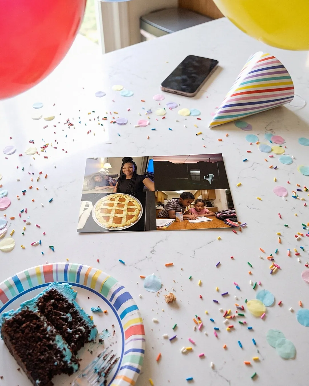 A photo postcard on a party table with confetti, a party hat and birthday cake