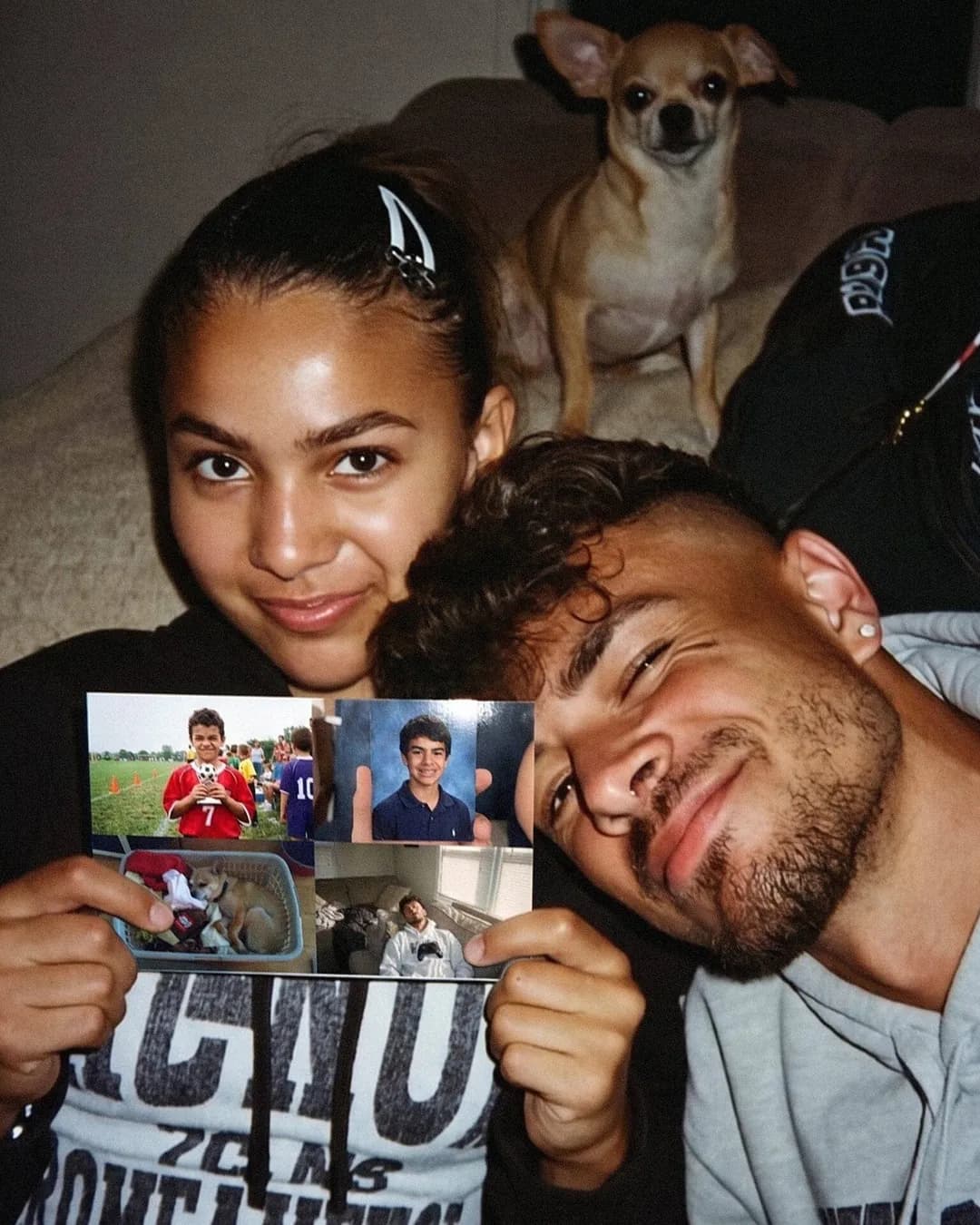 A young couple and their dog on the couch holding up a photo postcard