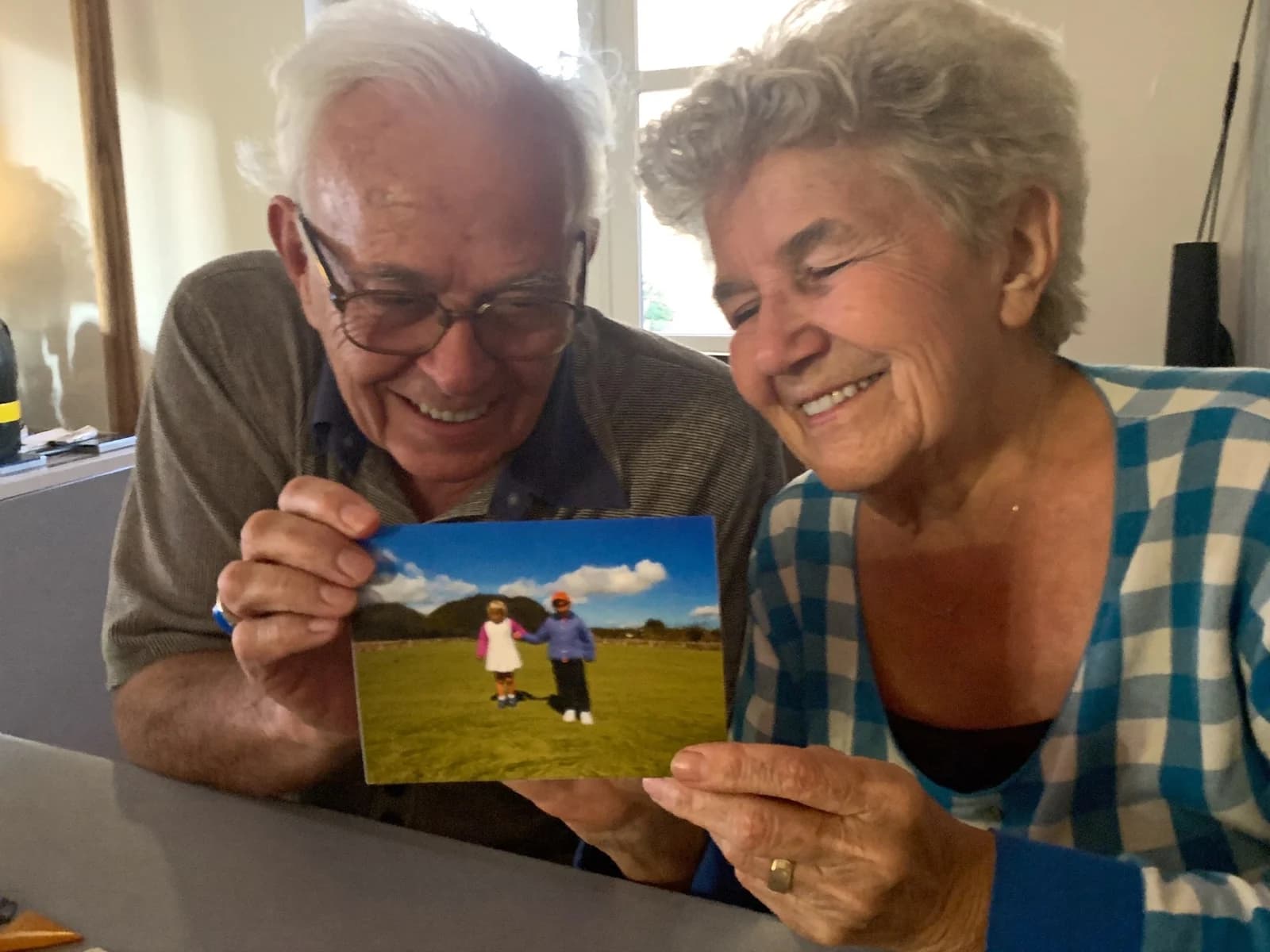 A grandmother and grandfather at their kitchen table reading a FamilyLetter postcard together