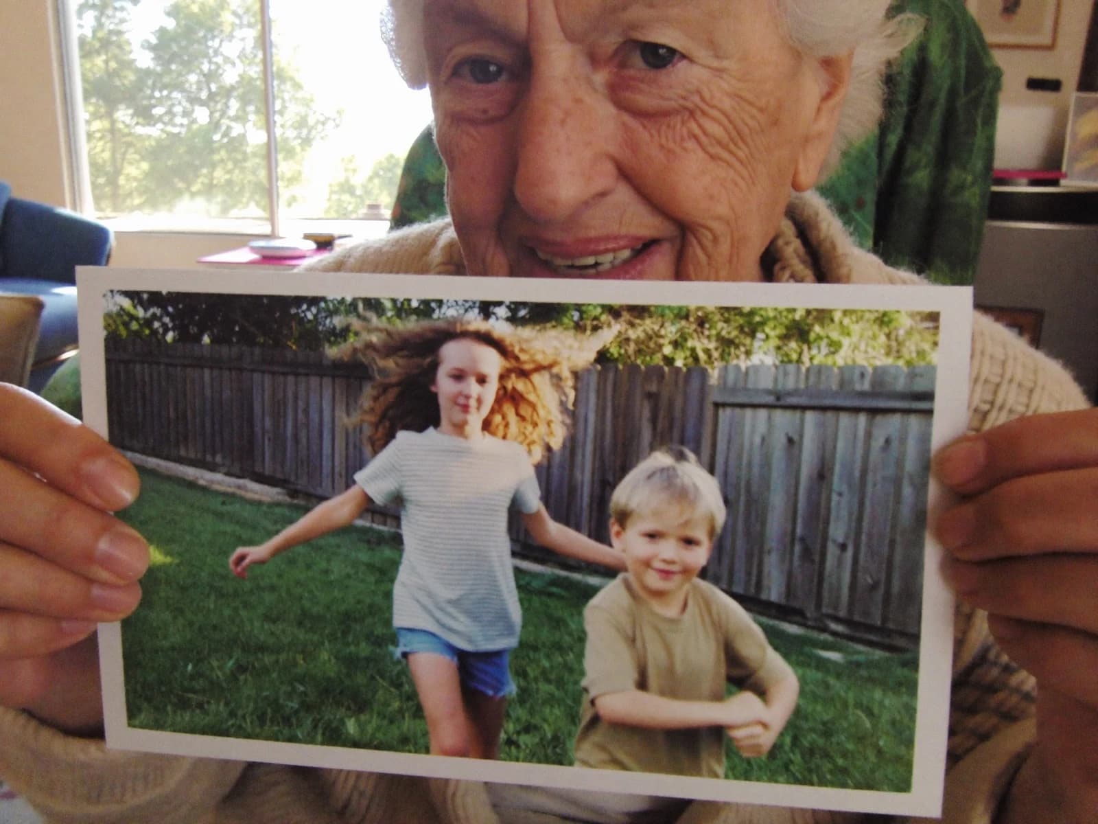 A grandmother holding a FamilyLetter postcard close to her, smiling as she looks at it