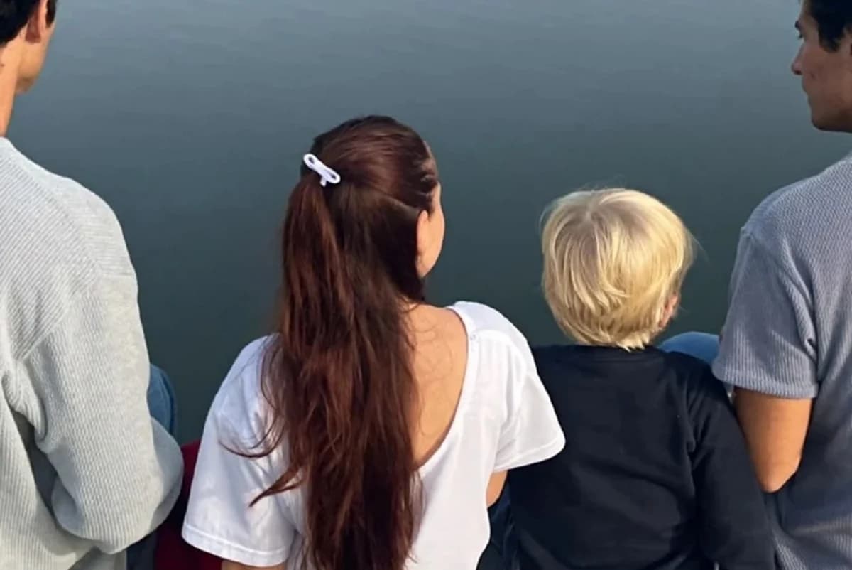 Card front with one photo of a family of four seen from behind, sitting on a wooden dock over a calm lake