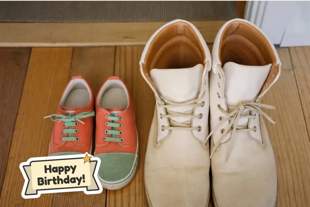 Card front with one photo of a child's orange sneakers beside a pair of worn white work boots, with a Happy Birthday sticker