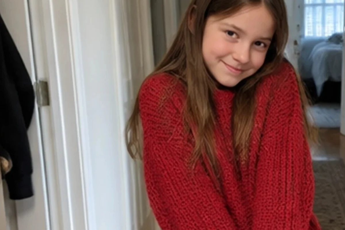 Postcard front with one full-size photo of a girl smiling in a chunky red sweater in a hallway