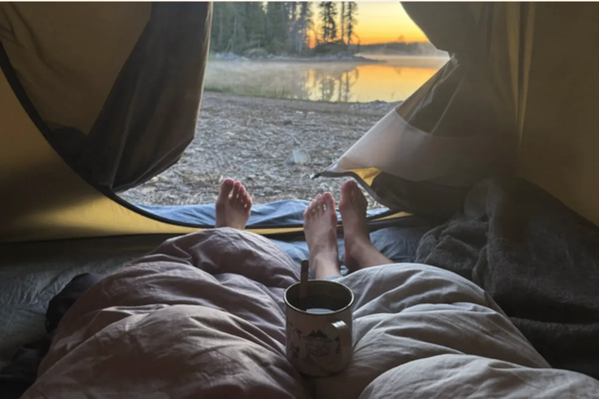 One-photo postcard front: a lake at sunrise seen from a tent